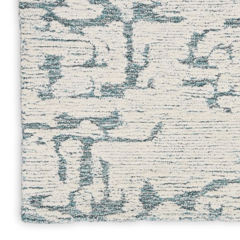 A close-up of a textured area rug with an abstract distressed pattern in muted blue-gray and off-white.