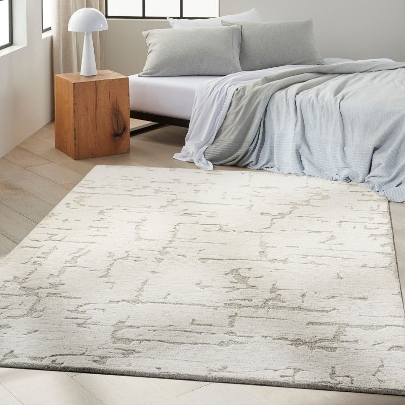 Modern bedroom with a textured area rug, bed, and wooden nightstand.