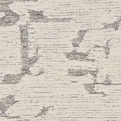 A close-up of a textured area rug with a distressed, abstract pattern in charcoal gray on an off-white background.