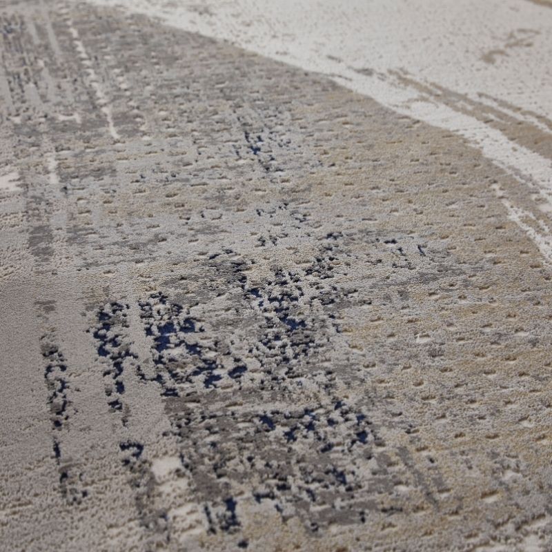 A close-up of a textured surface with a mottled pattern of beige, gray, and dark charcoal patches.