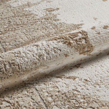 A close-up of a textured area rug with a distressed, pebbled stone-like pattern in cream, beige, and light brown tones, shown with a rolled section to highlight the pile and texture.