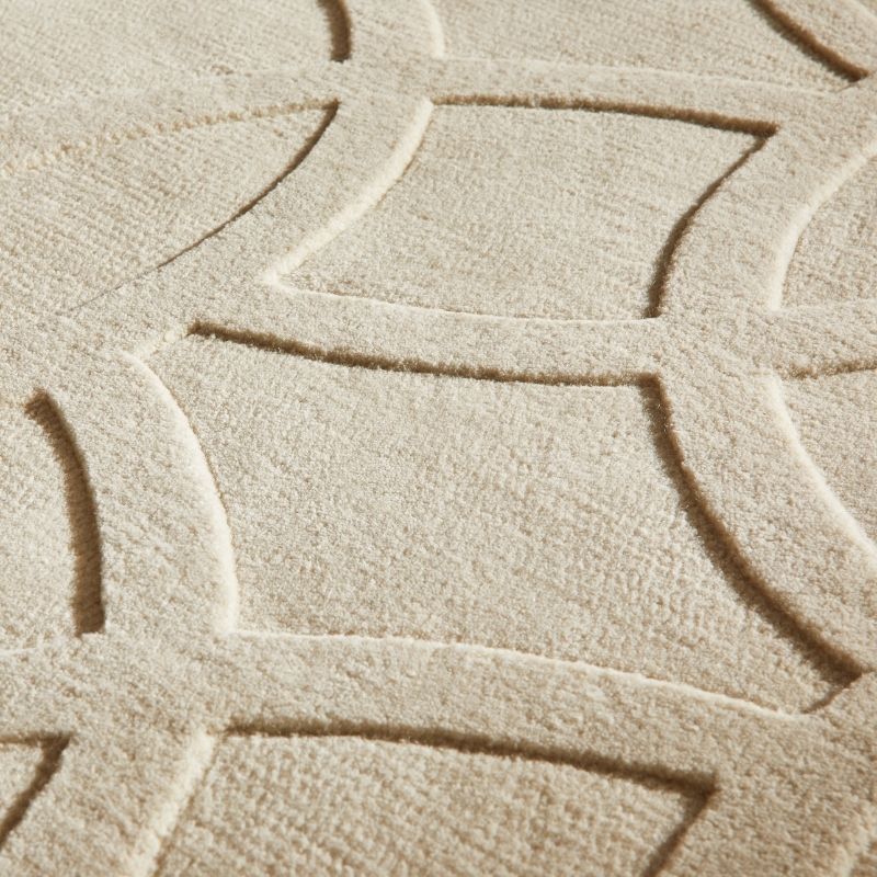 Close-up of a textured beige rug with a raised geometric lattice pattern.