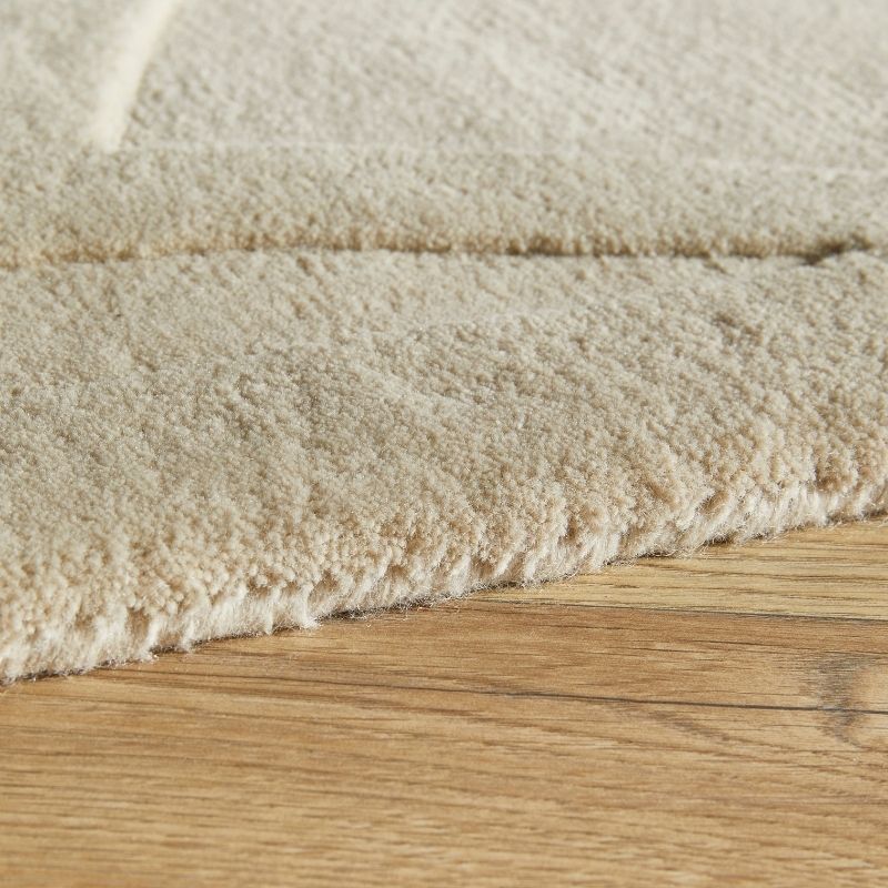 Close-up of a textured beige carpet edge on a wooden floor