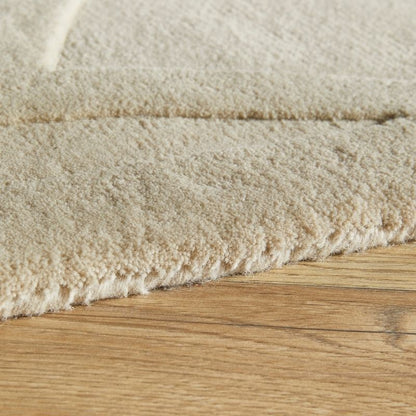 Close-up of a textured beige carpet edge on a wooden floor