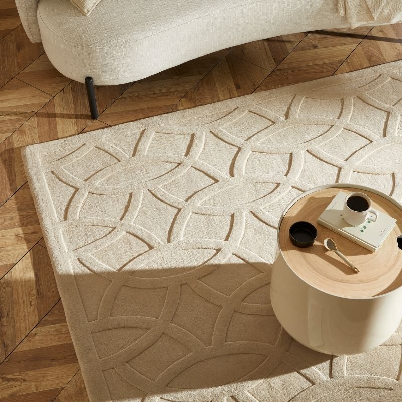 Beige textured rug with geometric pattern on a wooden floor