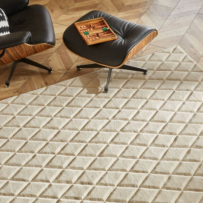 A textured cream-colored area rug with a raised diamond pattern, shown in a modern living room setting alongside mid-century style chairs and a wooden floor.