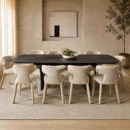 A modern dining room setup featuring a dark rectangular wooden table surrounded by eight upholstered dining chairs in a warm beige tone, set on a textured cream rug with a potted tree and wall art in the background.